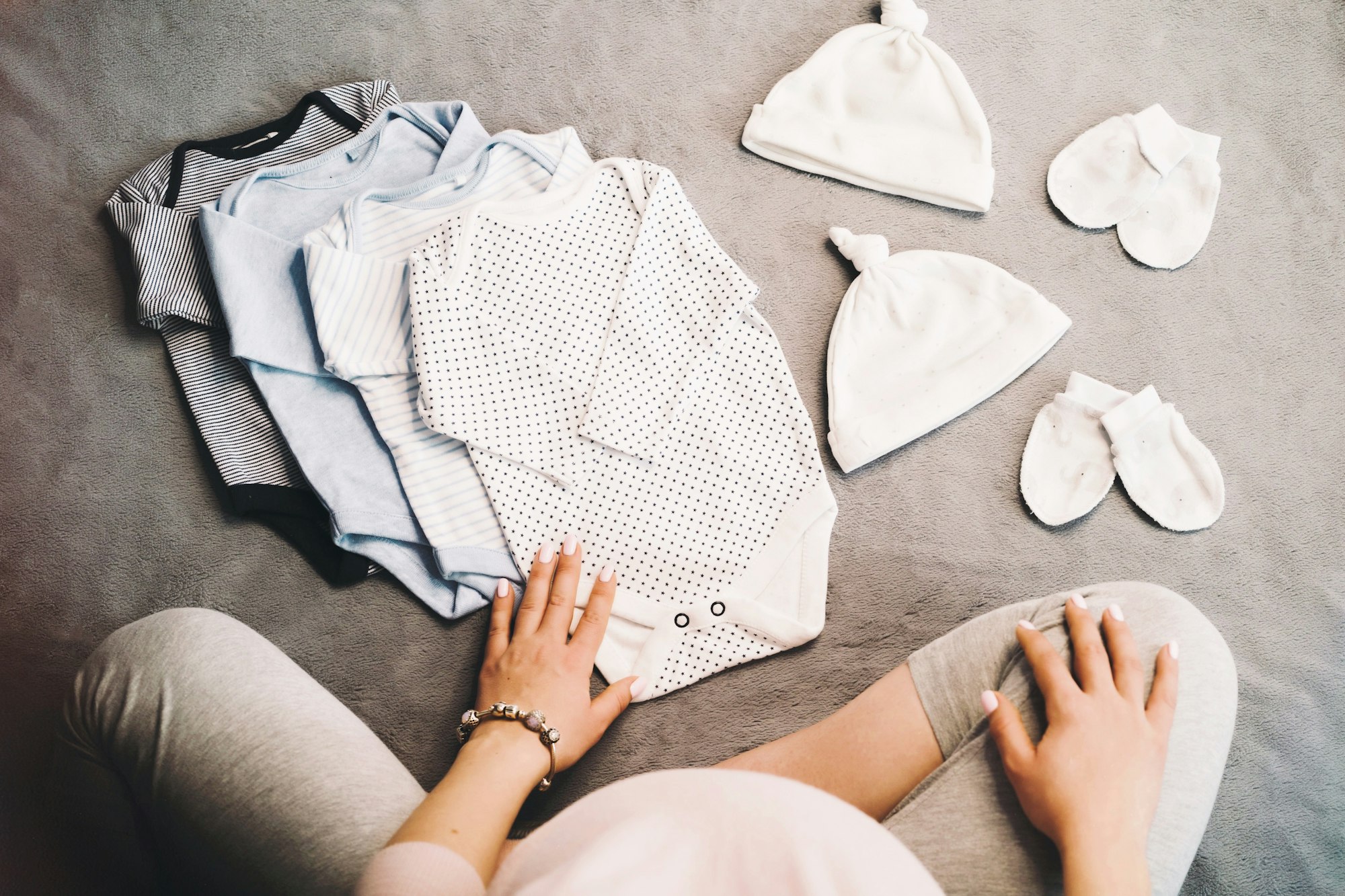 Pregnant Woman sitting with baby clothes